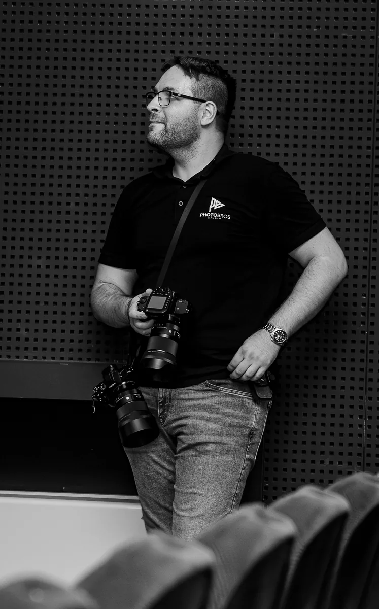 A PhotoBros photographer with two cameras waiting in a theatre, black and white